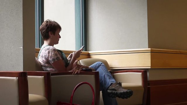 Woman texting good news from a hospital lobby over smartphone wifi
