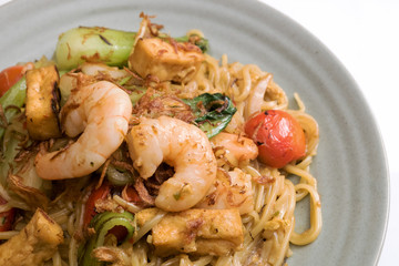 
Mie goreng, fried yellow noodle. with prawn seafood vegetable tomato choy egg garlic shallot onion shrimp cabbage on gray plate white table cloth. Deliciously famous indonesian Malaysian spicy dish.