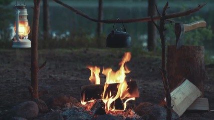 idyllic camp setup with tea pot over open fire and hanging kerosene lantern