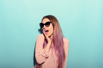 Portrait of excited beautiful woman with hand on chin. Studio shot on blue background