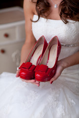 beautiful bride holding wedding shoes