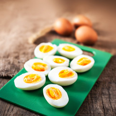 Hard boiled eggs, sliced in halves on cutting board wooden background close up image.