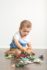 Little boy playing with dinosaur and animal action toys at home