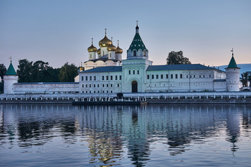 Fototapeta na wymiar Monastery in the rays of sunset/Ipatievsky Monastery in Kostroma. The domes are illuminated with searchlights.The monastery is on the river bank and is reflected in the river.Golden Ring of Russia