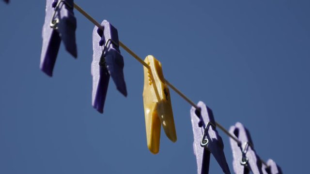 Yellow clothespin in row of purple close-up 3840X2160 UHD video - Plastic pegs against blue sky 2160p 30fps UltraHD footage