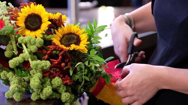 Florist ties a ribbon on the bouquet of sunflowers