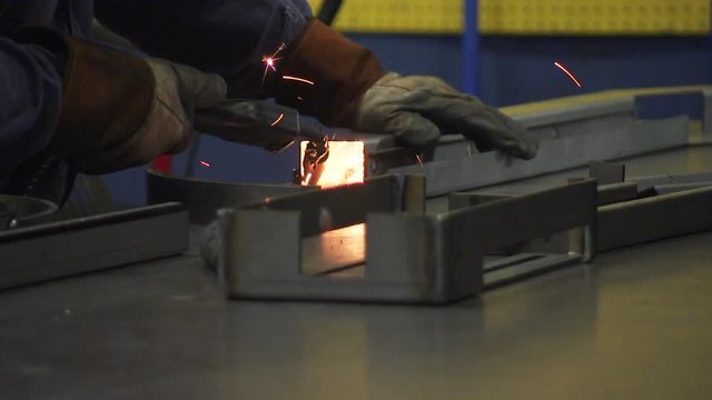 Worker uses welding torch on metal beam