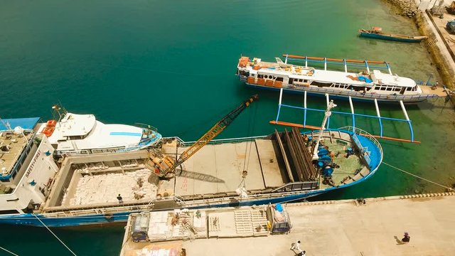 Cargo and passenger port with barges and cargo ships on tropical island. Aerial view:passenger ferry terminal Dapa city .Ferries for transport vehicles and passengers in the port. Philippines, Siargao