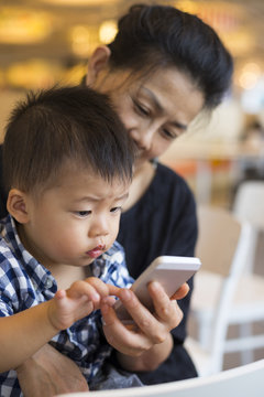 senior asian woman looking at mobile phone together with her gra