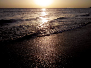 contraluz al atardecer en la playa con agua de mar y cielo en la ciudad de Cádiz, Andalucía....