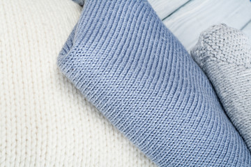 Knitted wool sweaters. Pile of knitted winter clothes on wooden background, sweaters, knitwear, space for text.