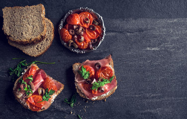 Sandwiches and ingredients on the dark background with blank space