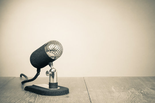 Old retro microphone from 50s on table. Vintage style sepia photo