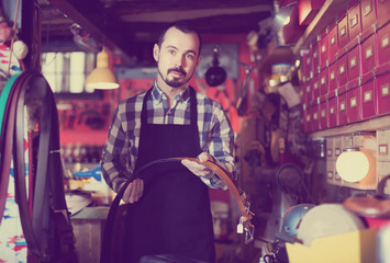 man worker displaying various belts in leather workshop