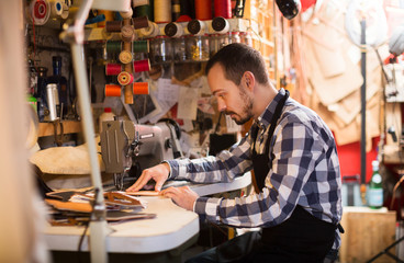 Fototapeta na wymiar Male worker stitching new belt