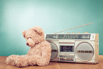 Retro toy Teddy Bear and radio tape recorder in front mint green background. Old instagram style...