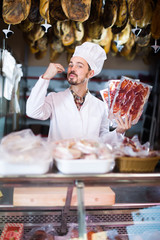 happy man seller showing sliced bacon in shop