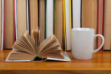 Naklejka premium Open book, red cup hardback colorful books on wooden table. Back to school. Copy space for text. Education business concept.