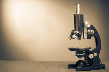 Retro old microscope on table. Vintage style sepia photo