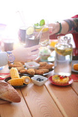 Top view of group of people having dinner together while sitting at wooden table. Food on the table. People eat fast food.