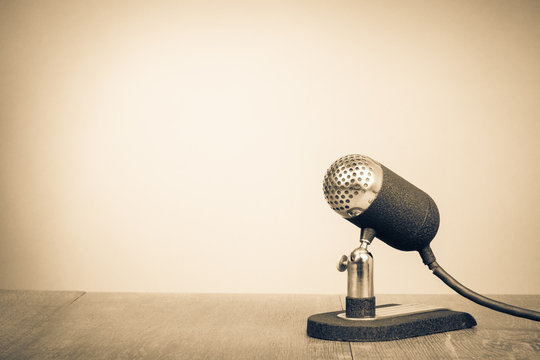 Retro old microphone from 50s on table. Vintage style sepia photo