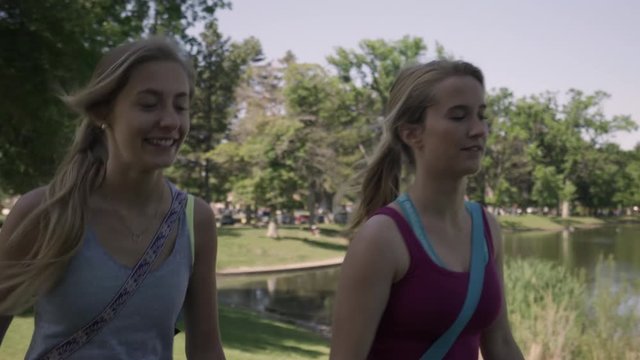 Steadicam Shot Of Fit Young Women Talking/Laughing And Walking Through Park On Their Way To Yoga Class