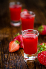 Portion of Strawberry liqueur on wooden background, selective focus