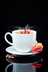 A macaroon splashes a cup of coffee on glass surface