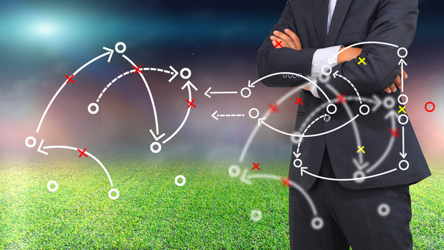 Football manager planning tactic with soccer field and bright spotlights.