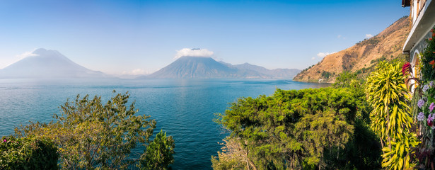 Scenic Panoramic View of Lake Atitlan and Volcanoes San Pedro and Toliman in Guatemala, from a charming resort with luxuriant tropical vegetation.