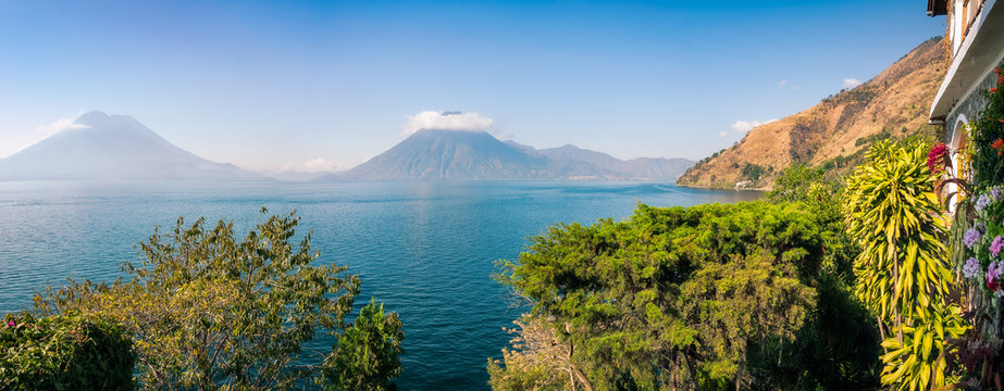 Scenic Panoramic View of Lake Atitlan and Volcanoes San Pedro and Toliman in Guatemala, from a charming resort with luxuriant tropical vegetation.
