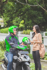 commercial motorcycle taxi driver giving helmet to his customer