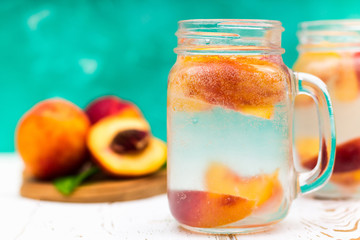 Homemade iced lemonade with ripe peaches. Fresh peach ice tea in a mason jar.