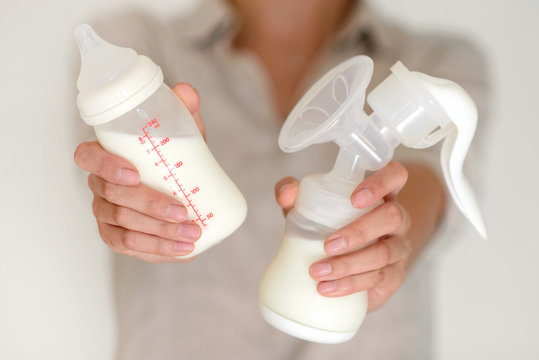 Breast pump and bottle with milk in woman's hand