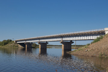 Concrete automobile bridge over the lake, reflected in that lake