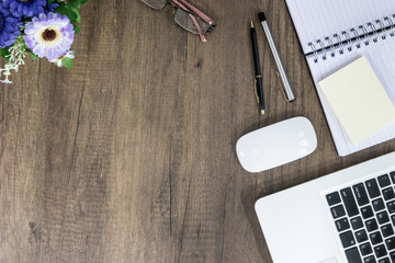 Office desk table Top view with laptop, supplies, notebook, pen, flower and blank white paper on wooden table background. Top view with copy space