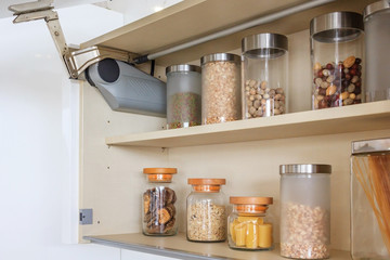 Kitchen cabinet with opened fronts with Kitchen bench shelves with various food ingredients on...