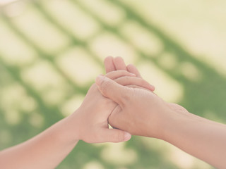 Retro style of woman  holds the hand of a lovely child. Mother and son holding hands in the background of the green field. People, charity and family concept.