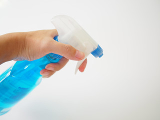 Left hand holding blue solution foggy spray bottle, white background