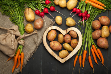Fresh vegetables and heart on a black wooden background. Rustic style