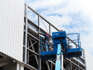 construction worker at construction site using lifting boom machinery