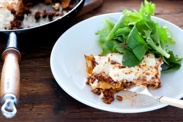 homemade lasagne served in a plate with salad