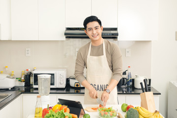 Young asian handsome man preparing food in kitchen at home