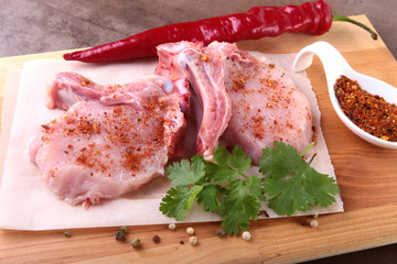Raw pork steak with spices Leaves of coriander on wooden cutting board. Ready for cooking.