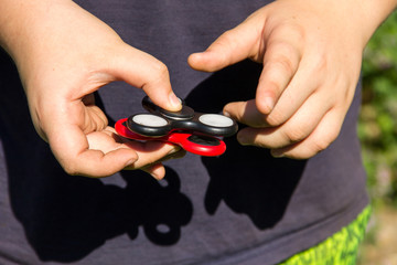 Boy playing with two fidget spinner stress relieving toys outdoor