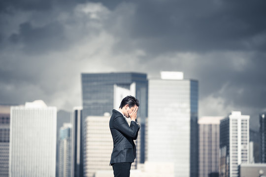 Fear, worry, stress. Stressed businessman in the city with dark storm clouds over head. 