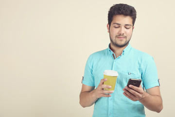 The guy drinks coffee and reads on the smartphone