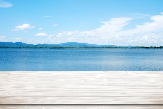 Empty white wood table over blur blue sea and sky background, nature background, spring and summer, tropical climate, travel concept, for product display montage