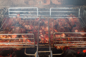 Grilled meat in barbecue with flames and coals.