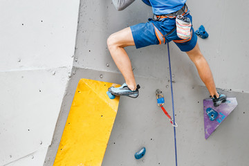 Foot of a sportsman climber on artificial boulder gym wall. Close-up view